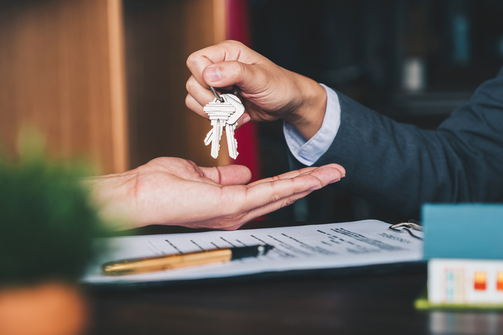 estate agent giving house keys to woman and sign agreement in office